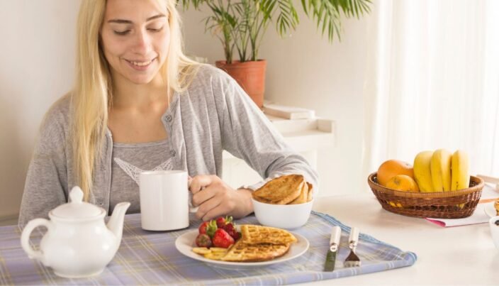 Dicas de café da manhã saudável para diabéticos 1 Pessoa apreciando um café da manhã para diabéticos, com torrada integral crocante, banana madura, morangos frescos e uma xícara de café sem açúcar, em uma mesa bem posta e iluminada.